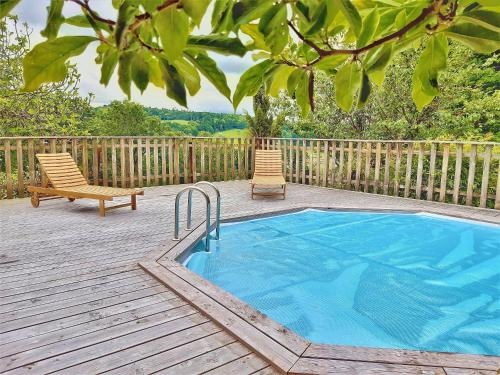 een zwembad op een terras met 2 stoelen en een bank bij Villa Saint Kirio - piscine et spa in Morlaix