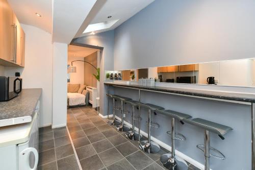 a kitchen with a bar with stools at Comfy 4 bed house close to station and theatre in London