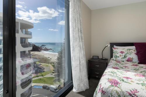 - une chambre avec une fenêtre donnant sur l'océan dans l'établissement Oceanside Apartment with Iconic Views, à Mount Maunganui