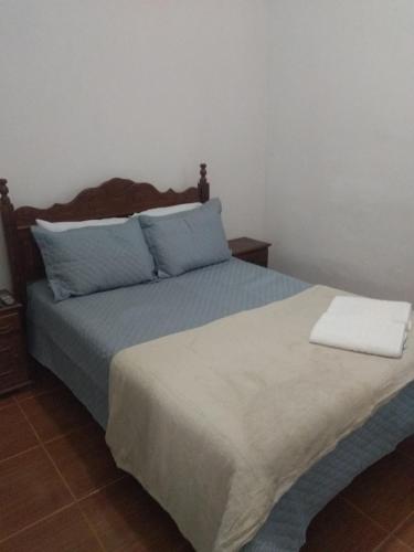 a bedroom with a large bed with blue pillows at Pousada Santo Expedito in Tiradentes