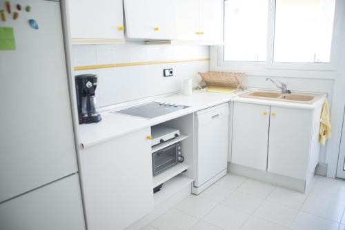 una cocina blanca con armarios blancos y fregadero en Appartment Kristal Mar II, en Moraira