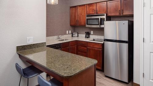 La cuisine est équipée d'un réfrigérateur en acier inoxydable et de placards en bois. dans l'établissement Residence Inn by Marriott Tucson Williams Centre, à Tucson