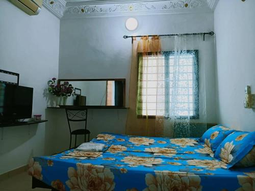 a bedroom with a bed with a blue comforter and a window at Globe-trotter vision C in Cotonou