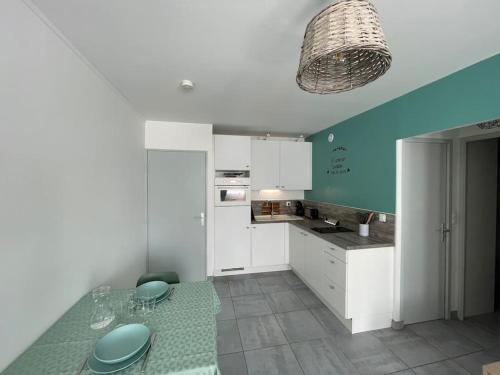 une cuisine avec des armoires blanches et un mur bleu dans l'établissement Appartement 2 pièces, lumineux, avec parking, à Cabourg