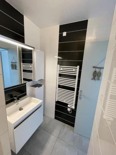 une salle de bain blanche avec un lavabo et un miroir dans l'établissement Appartement 2 pièces, lumineux, avec parking, à Cabourg