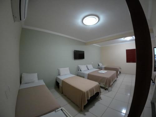 a room with three beds and a tv at Hotel Pousada da Lapa in Bom Jesus da Lapa