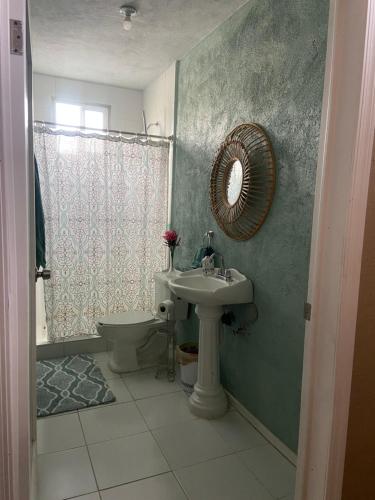 La salle de bains est pourvue d'un lavabo, de toilettes et d'un miroir. dans l'établissement Large 4 bedroom home with gated parking, à Puerto Peñasco