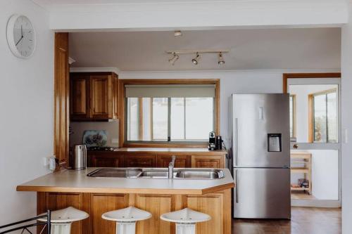 a kitchen with a stainless steel refrigerator and wooden cabinets at OceanFront - Absolute Waterfront in Bicheno