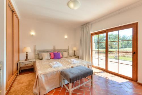 a bedroom with a bed and a large window at Quinta dos Tesouros in São Brás de Alportel