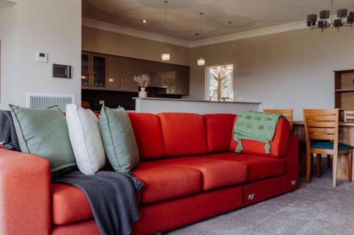 a red couch with pillows in a living room at Apartment on James in Bicheno