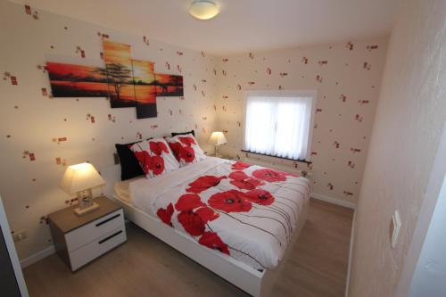 Un dormitorio con una cama con flores rojas. en Skyline, en Ypres