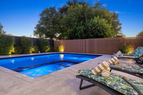 a swimming pool in a backyard with a bench next to it at Villa Alessandro - Mornington Peninsula Luxury Accommodation in Tootgarook