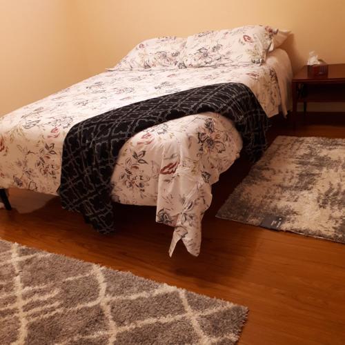 a bedroom with a bed and a rug on a wooden floor at in beacon hill in Ottawa