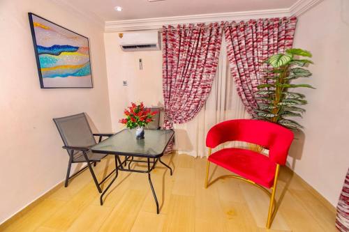 uma sala de jantar com uma cadeira vermelha e uma mesa em Blaze by Treston Grand Apartment, Maitama em Abuja
