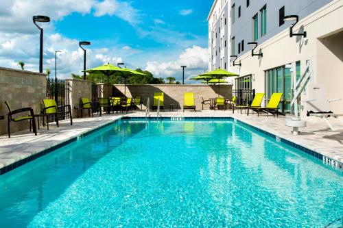 a pool with chairs and umbrellas next to a building at SpringHill Suites by Marriott Tampa Suncoast Parkway in Land O' Lakes