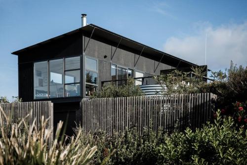 una casa negra con ventanas de cristal y una valla en Moonbird Beach Shack ~ Ocean Escape, en Beaumaris Tasmania