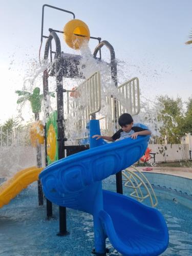 un ragazzo su uno scivolo d'acqua in piscina di منتجع القصر الأبيض a Unayzah