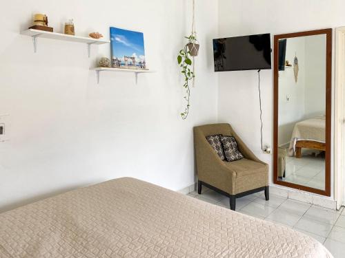- une chambre avec un lit, une chaise et un miroir dans l'établissement Cómodo y bonito estudio en Cozumel, à Cozumel