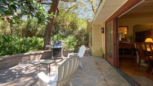 a patio with two white chairs and a grill at HACIENDA - 3-Bedroom Home home in Jekyll Island