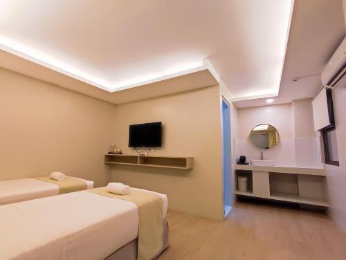 a hotel room with two beds and a tv at Hotel Simone Kalibo in Kalibo