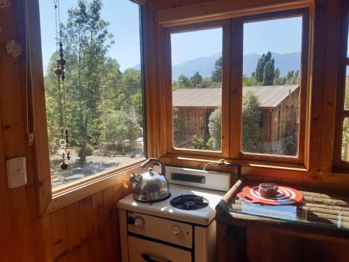 a kitchen with two windows and a tea kettle on a stove at Cabañas Puente Negro in Puente Negro
