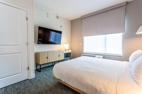 a bedroom with a bed and a flat screen tv at TownePlace Suites by Marriott Raleigh - University Area in Raleigh