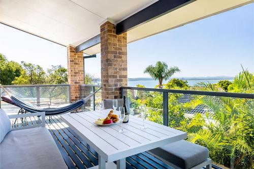 a white table and chairs on a balcony at Away Nelson Bay, 29 Wollomi Ave - Spacious family home with water views, pet friendly, Wifi & aircon in Nelson Bay