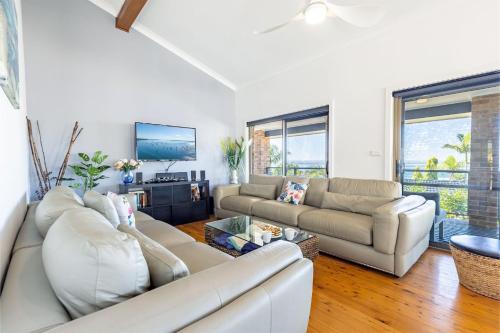 a living room with two couches and a tv at Away Nelson Bay, 29 Wollomi Ave - Spacious family home with water views, pet friendly, Wifi & aircon in Nelson Bay
