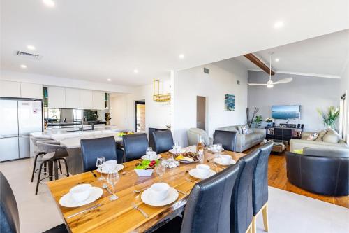 a dining room and living room with a table and chairs at Away Nelson Bay, 29 Wollomi Ave - Spacious family home with water views, pet friendly, Wifi & aircon in Nelson Bay