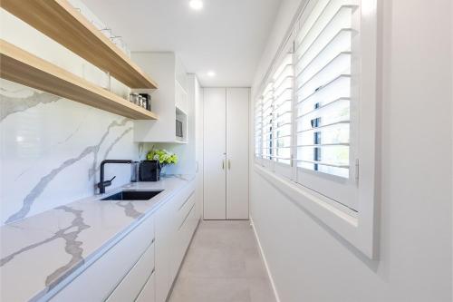 a kitchen with white cabinets and a sink and a window at Away Nelson Bay, 29 Wollomi Ave - Spacious family home with water views, pet friendly, Wifi & aircon in Nelson Bay