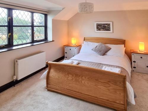 een slaapkamer met een groot bed en 2 ramen bij Cobweb Cottage in Ludham