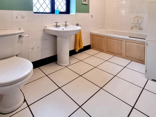 een badkamer met een toilet, een wastafel en een bad bij Cobweb Cottage in Ludham