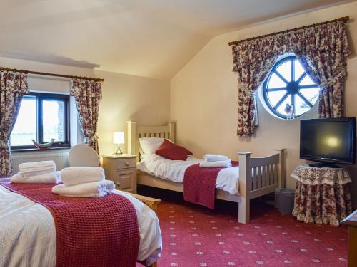 1 dormitorio con 2 camas individuales y TV en Priory Barn, en Burscough