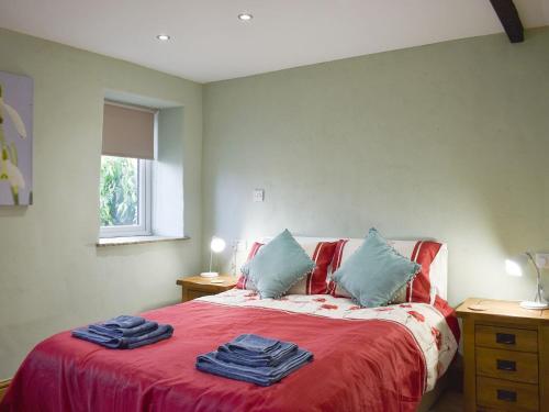een slaapkamer met een bed met rode lakens en blauwe kussens bij Snowdrop Cottage in Staveley