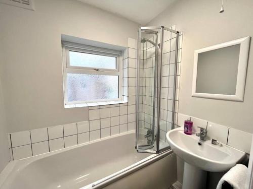 a bathroom with a sink and a bath tub and a window at 4 bedroom home 10 mins to city in Gateshead