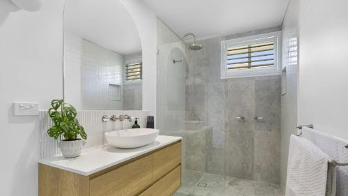 a white bathroom with a sink and a shower at Malolo in Yamba