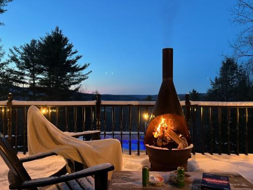 a fire pit on a deck with a table and a chair at Catskills Cabin: Hot Tub, Firepit, WFH, Ski, Games in Lexington