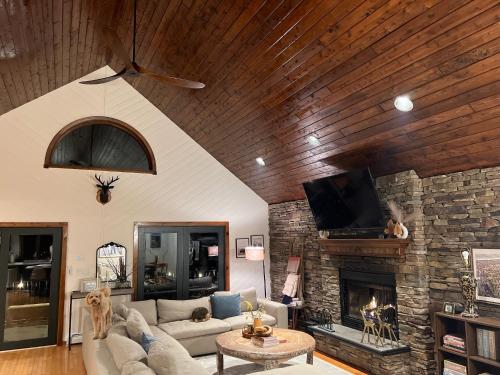 a living room with a couch and a stone fireplace at Catskills Cabin: Hot Tub, Firepit, WFH, Ski, Games in Lexington
