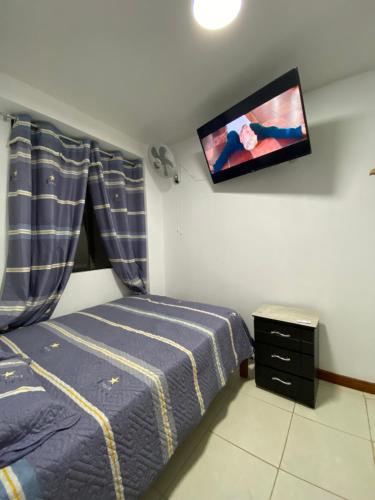 a bedroom with a bed and a flat screen tv at Hostal Venus - Nueva Imagen in Huacho