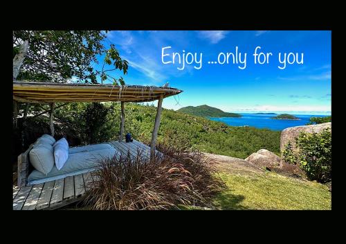 a bed with a canopy on a hill next to the ocean at Château de feuilles & SPA - Praslin island in Baie Sainte Anne
