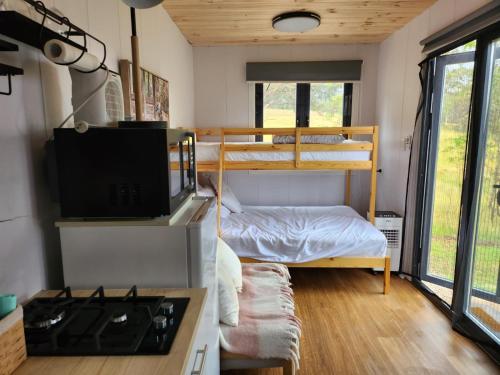 um pequeno quarto com um beliche e um fogão em Tiny Home - Bluebird em Hartley