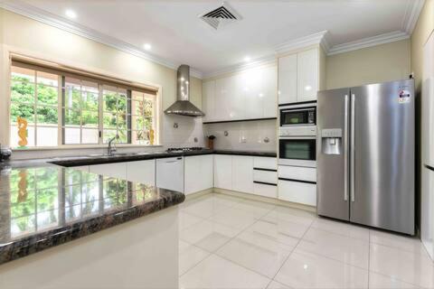 a large kitchen with a stainless steel refrigerator at Luxury 5 Bedroom home, Steps to Beach Sol in Port Douglas
