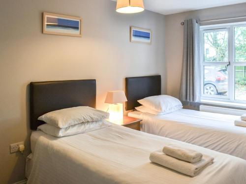 two beds in a room with a window at Sea Shells in Sutton on Sea