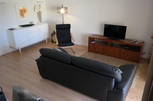 a living room with a black couch and a tv at Vila Atlantida Apartment in Vilamoura