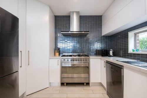 a kitchen with white cabinets and a stainless steel stove at Family Tides Beach House in Rosebud