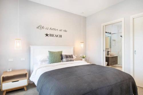 1 dormitorio con 1 cama y un cartel en la pared en Family Tides Beach House, en Rosebud