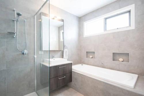 a bathroom with a tub and a sink and a shower at Family Tides Beach House in Rosebud