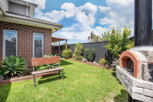 a garden with a bench in front of a house at Family Tides Beach House in Rosebud