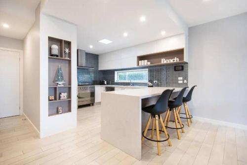 a kitchen with a bar with stools at a counter at Family Tides Beach House in Rosebud
