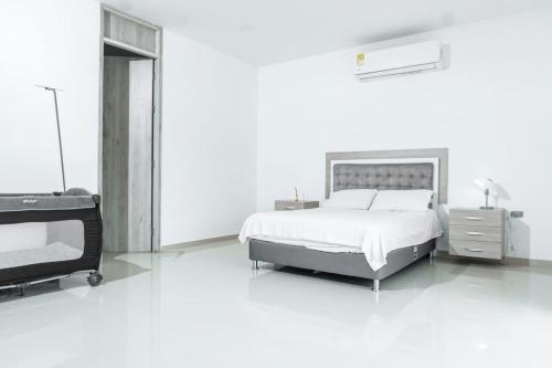 a white bedroom with a bed and a tv at Casa finca con piscina in Santa Marta